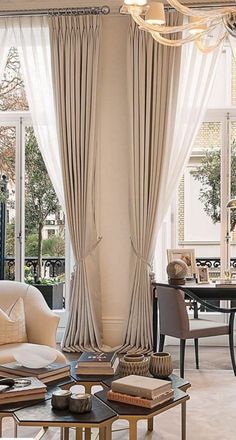 a living room filled with lots of furniture next to a large glass window covered in curtains