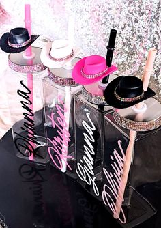 three clear jars with hats on them sitting on a table next to a glitter wall