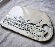 a ceramic dish with flowers on it sitting on a cloth covered tablecloth in front of a white background