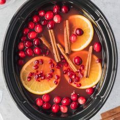 oranges, cranberries and cinnamon sticks in a blender filled with liquid