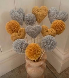 a vase filled with balls of yarn and pom - poms on top of a table