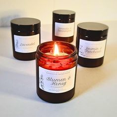 three candles sitting next to each other on a white table top with labels around them