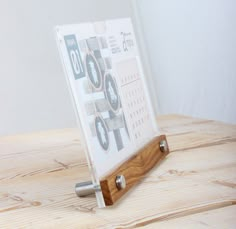 a wooden table with a glass and metal holder on it's side, sitting on top of a wood surface