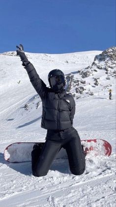 a person sitting in the snow with their arms up