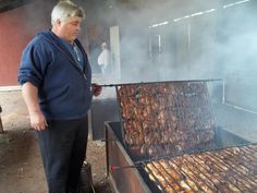 a man standing next to a grill filled with food