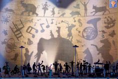 the shadow of an elephant in front of a stage with people on it and musical notes