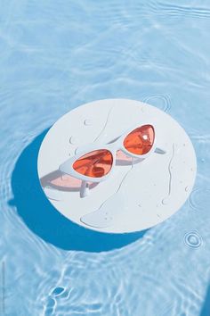 pair of sunglasses sitting on top of a white object floating in the middle of a pool