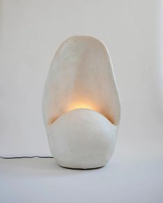 an egg shaped lamp is lit up on a white surface with a cord attached to it