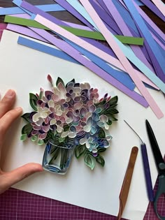 someone is making a paper flower bouquet out of strips of colored construction paper and scissors