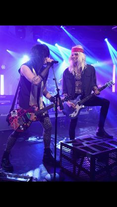 two people on stage with guitars and microphones