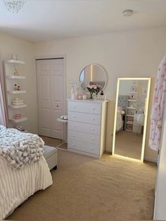 a bedroom with a bed, dresser, mirror and lights on the wall in front of it