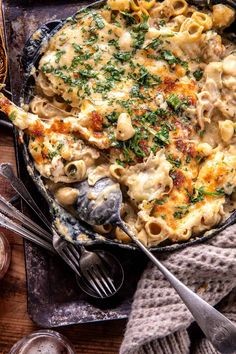 a skillet filled with macaroni and cheese on top of a wooden table