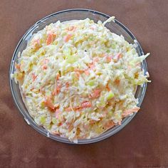 a bowl filled with coleslaw and carrots on top of a brown table