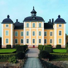 a large yellow building surrounded by hedges and trees