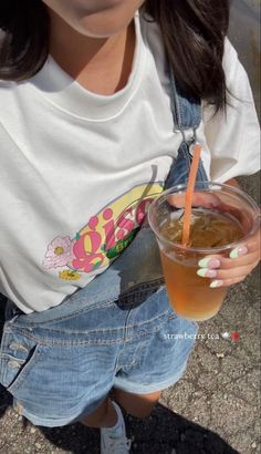 a woman is holding a drink in one hand and an orange straw in the other