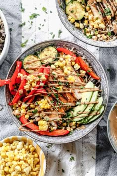 three bowls filled with grilled vegetables and rice on top of a white table cloth