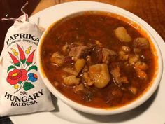 a bowl of soup on a plate with a bag of kaloks next to it