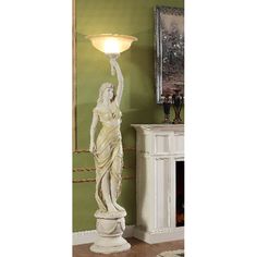 a white statue with a light on it in front of a green wall and fireplace