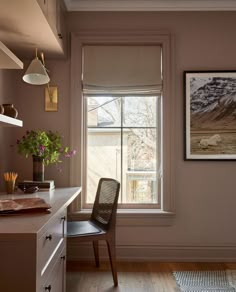 a chair sitting in front of a window next to a wooden table with flowers on it