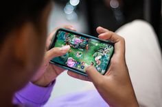 a person holding a cell phone in their hand and playing with the game on it