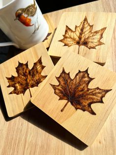 four maple leaf coasters on a table with a coffee cup in the back ground