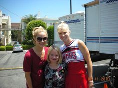 two women and a girl standing in front of a trailer