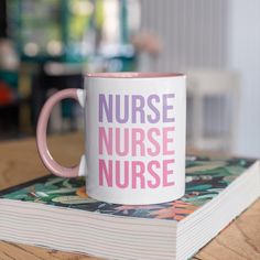 a pink and white coffee mug sitting on top of a book