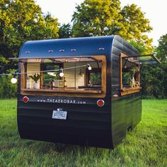 an old bus converted into a mobile bar in the middle of a grassy area with trees behind it