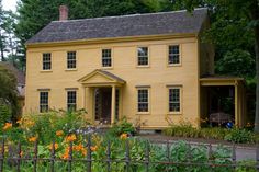 a yellow house surrounded by trees and flowers