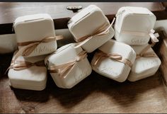 a bunch of white boxes with brown ribbons on them sitting on top of a wooden table