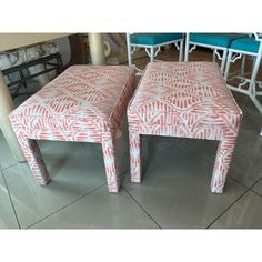 a pair of pink and white patterned stools on tile floor next to blue chairs