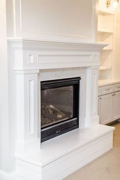 a white fireplace with a black fire place in the center and shelves on either side