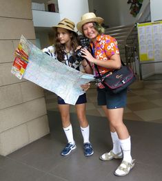 two young women standing next to each other holding a map