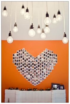 a heart made out of photos hangs from the ceiling in front of an orange wall