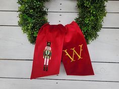 a wreath with a nutcracker on it next to a red velvet bag that says w