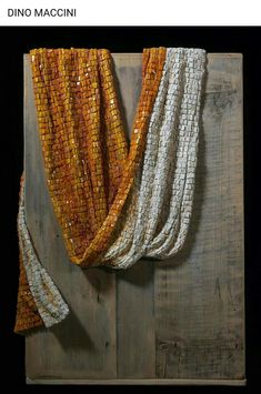 an orange and white scarf is hanging on a wooden wall next to a piece of wood