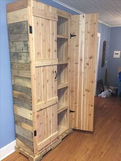 a large wooden cabinet sitting on top of a hard wood floor next to a blue wall