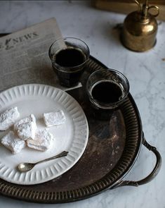 a plate with marshmallows and two cups of coffee