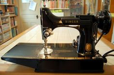 an old black sewing machine sitting on top of a wooden table next to a bookshelf