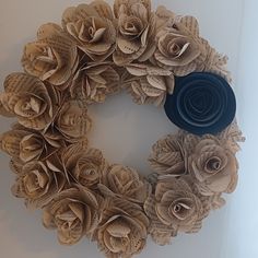 a wreath made out of old book pages and rolled up with a blue felt flower