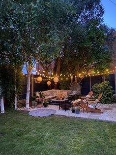 an outdoor patio with lights strung over it and furniture in the middle of the yard