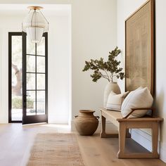 an entryway with a bench and vases on the floor next to a door