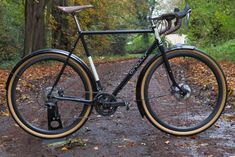 a bike parked on the side of a dirt road in front of trees and leaves