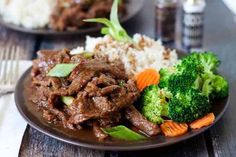 beef and broccoli on a plate with rice, carrots and gravy