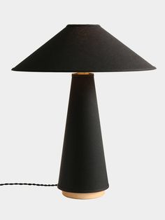 a black lamp on a white background with a cord in front of it and the light turned off