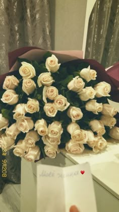 a bouquet of white roses sitting on top of a table next to a card that says i love you