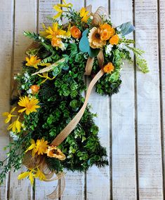 a wreath with yellow flowers and greenery tied to it