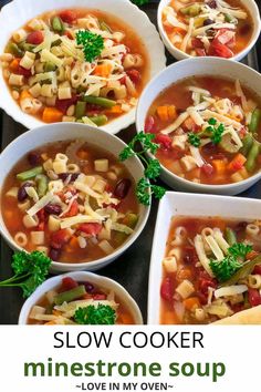 several bowls of soup are on a tray with bread and parsley in the background