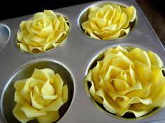 four cupcakes with yellow frosting in a muffin tin