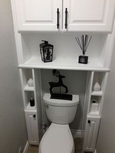 a white toilet sitting under a shelf filled with candles